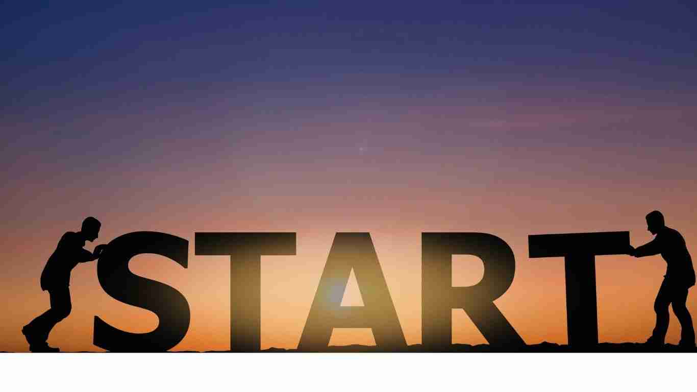 Silhouettes pushing START letters at sunset.